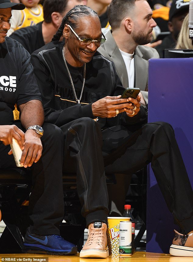 Wearing matching gold sneakers, he enjoyed some popcorn and Coke while sitting in his courtside seat laughing at something on his phone