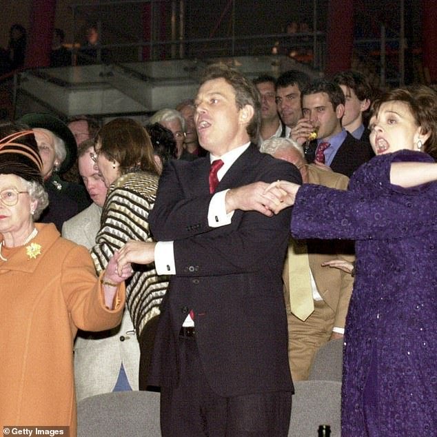 Queen Elizabeth II, British Prime Minister Tony Blair and his wife Cherie Blair join hands for Auld Lang Syne in 1999