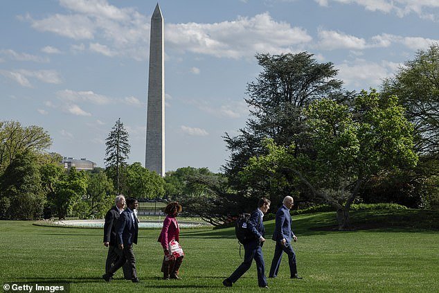 President Joe Biden walks across the South Lawn after landing on Marine One with senior members of his staff, including Bruce Reed and Karine Jean-Pierre