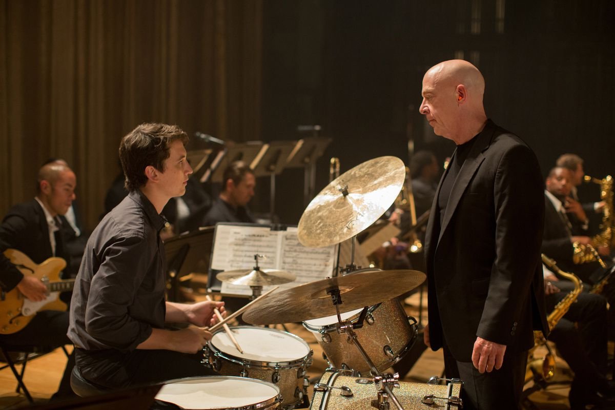 Andrew Neiman (Miles Teller) sits at a drum set across from his bandleader Fletcher (JK Simmons) in Whiplash.