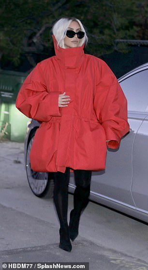 The SKIMS founder, 43, showed off her impeccable sense of style in an oversized red coat, tights and black stilettos