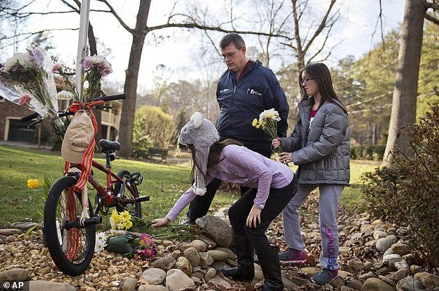Children place flowers at a makeshift memorial outside 69-year-old Elrey's home "Knob" Runion and his 66-year-old wife, June, Tuesday, January 27, 2015, in Marietta, Georgia
