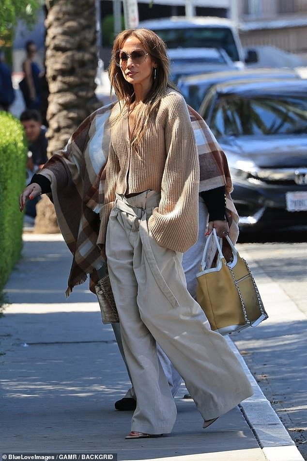 The 54-year-old pop star continued her baggy pants parade in khaki wide-leg trousers with a belt, paired with peep-toe heels and a cropped cardigan with brown ribbed bell sleeves.