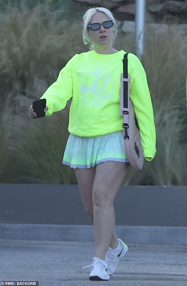 The 38-year-old superstar showed off her athletic legs and her unique style in a gray skirt with a neon yellow stripe and a bright neon yellow sweater.  The LoveGame singer covered up her left hand amid rumors she and boyfriend Michael Polansky were engaged