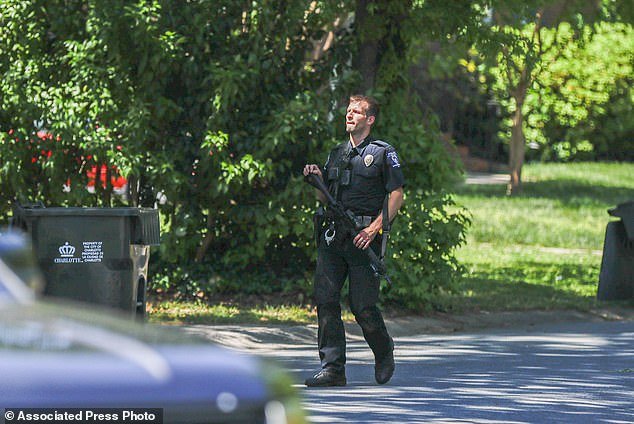 A Charlotte Mecklenburg police officer carries a gun as he walks through the neighborhood where an officer-involved shooting occurred in Charlotte