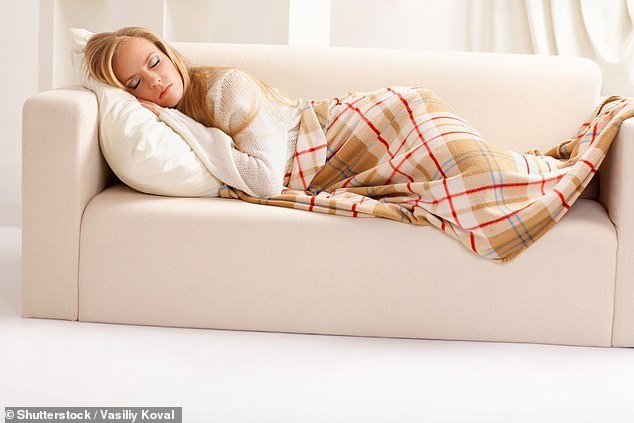 A woman sleeps on a couch under a blanket.  Scientists say weighted blankets trigger the release of feel-good chemicals in the brain, which respond to the pressure of the blanket like a hug or hug (stock image)