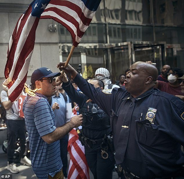 Police try to rescue a pro-Israel supporter, center, by removing his American flag that was set on fire by someone else during a pro-Palestinian demonstration