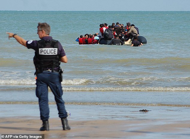 File image shows a police officer on a beach in northern France during the departure of a boat carrying migrants trying to illegally cross the English Channel to reach Britain