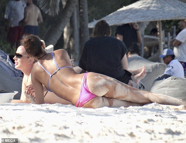 After splashing in the ocean with a friend, the TV personality showed off her sandy backside as she lay on the beach