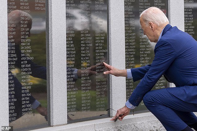 President Joe Biden reaches out to name his uncle Ambrose J. Finnegan, Jr.  to touch, on a wall at a war memorial in Scranton, Wednesday, April 17, 2024, in Scranton, Pennsylvania.  His uncle died in World War II