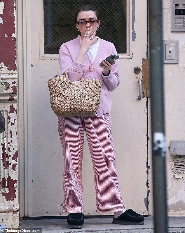 Maisie Williams, 27, puffed on a cigarette as she donned a trendy pink outfit in New York on Thursday, including striped pajama bottoms and backless slippers