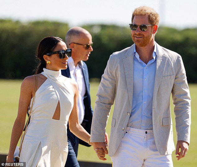 Meghan embraced the bright sunshine in an elegant white dress with a pleated skirt, halter top and cutout at the waist