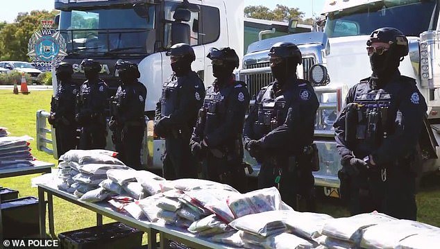 Police officers stand behind a table holding millions of dollars seized from a truck