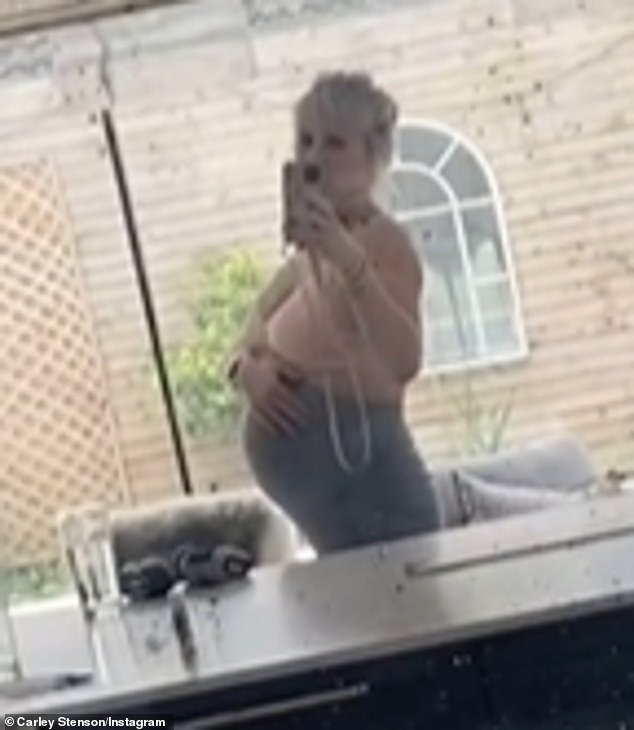 The pregnant former Hollyoaks star, 41, cradled her bump while wearing a pink sports bra and gray leggings