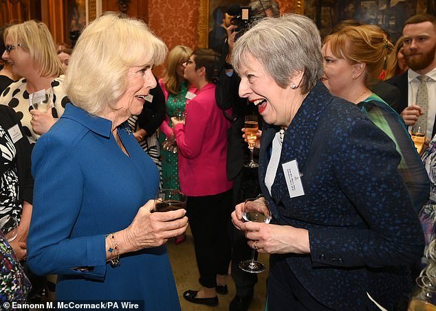 Pictured: Queen Camilla enjoys a conversation with former British Prime Minister Theresa May