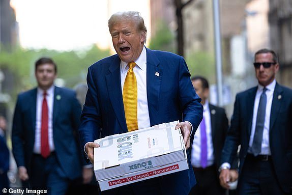 NEW YORK, NEW YORK - MAY 2: Republican presidential candidate, former US President, Donald Trump carries boxes of pizza in front of the FDNY Engine 2, Battalion 8 firehouse on May 2, 2024 in New York City.  Trump delivered pizza to a fire station after a court appearance in his hush-money trial, which began with a hearing in which prosecutors argued that Judge Juan Merchan should again charge Trump with criminal contempt for violating a silence order.  Earlier this week, Trump was charged with contempt for nine violations of his April 1 order banning criticism of witnesses and jurors.  (Photo by Michael M. Santiago/Getty Images) ***BESTPIX***