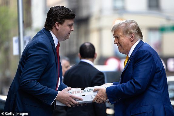 NEW YORK, NEW YORK - May 2: Republican presidential candidate, former US President Donald Trump, is handed boxes while delivering pizza to the FDNY Engine 2, Battalion 8 fire station on May 2, 2024 in New York City.  Trump delivered pizza to a fire station after a court appearance in his hush-money trial, which began with a hearing in which prosecutors argued that Judge Juan Merchan should again charge Trump with criminal contempt for violating a silence order.  Earlier this week, Trump was charged with contempt for nine violations of his April 1 order banning criticism of witnesses and jurors.  (Photo by Michael M. Santiago/Getty Images)