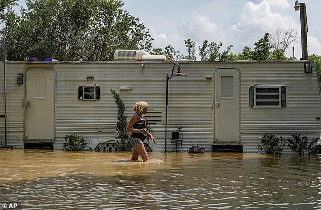 A woman is seen fighting her way through brown floodwaters as she heads to an elderly resident in his RV in Channelview, Texas