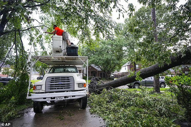 A utility worker is seen repairing power lines after a huge tree fell on a home in Spring, Texas