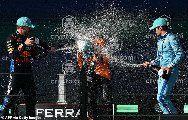 Norris is showered with champagne by Verstappen and Ferrari's Charles Leclerc (right)