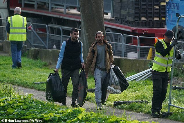 Asylum seekers leave with their belongings during an early morning operation by Irish authorities to remove tents