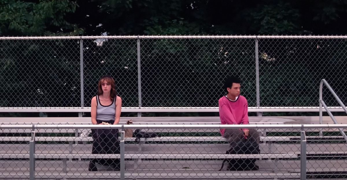 Super awkward teenage friends Maddy (Brigette Lundy-Paine) and Owen (Justice Smith) sit far apart in the metal bleachers of their school in I Saw the TV Glow