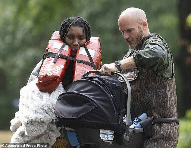 A woman is handed her child after being evacuated from her home by boat Friday with the help of deputies from the Montgomery County Sheriff's Office