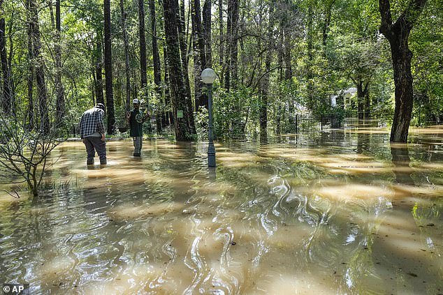 People are seen walking through murky water in McDade, Texas on Thursday
